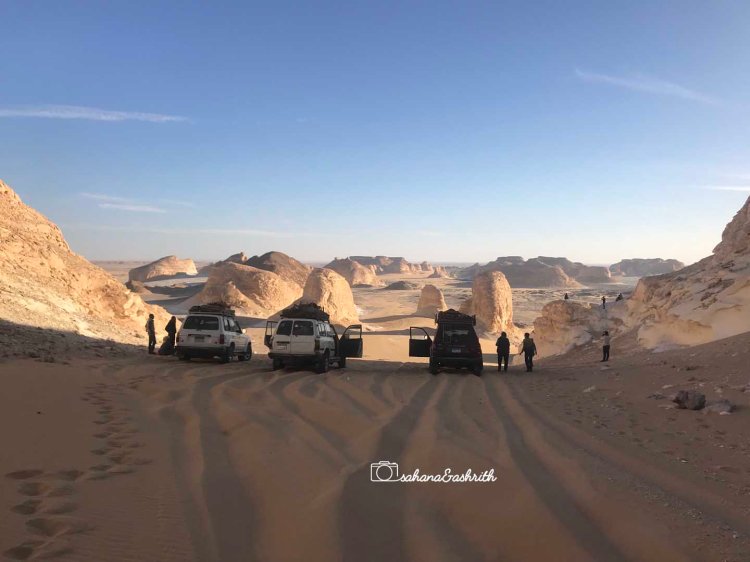 Desert road of sanddunes opening to a vallley full of white egg shaped lime stone mountains in Egypt