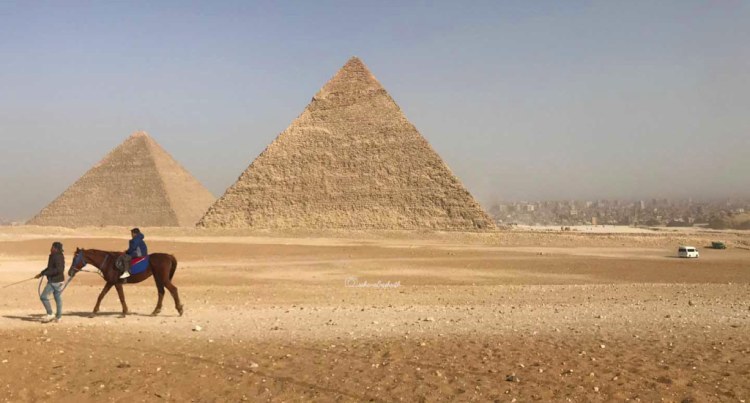 Horse riding in front of two Giza pyramids in Egypt