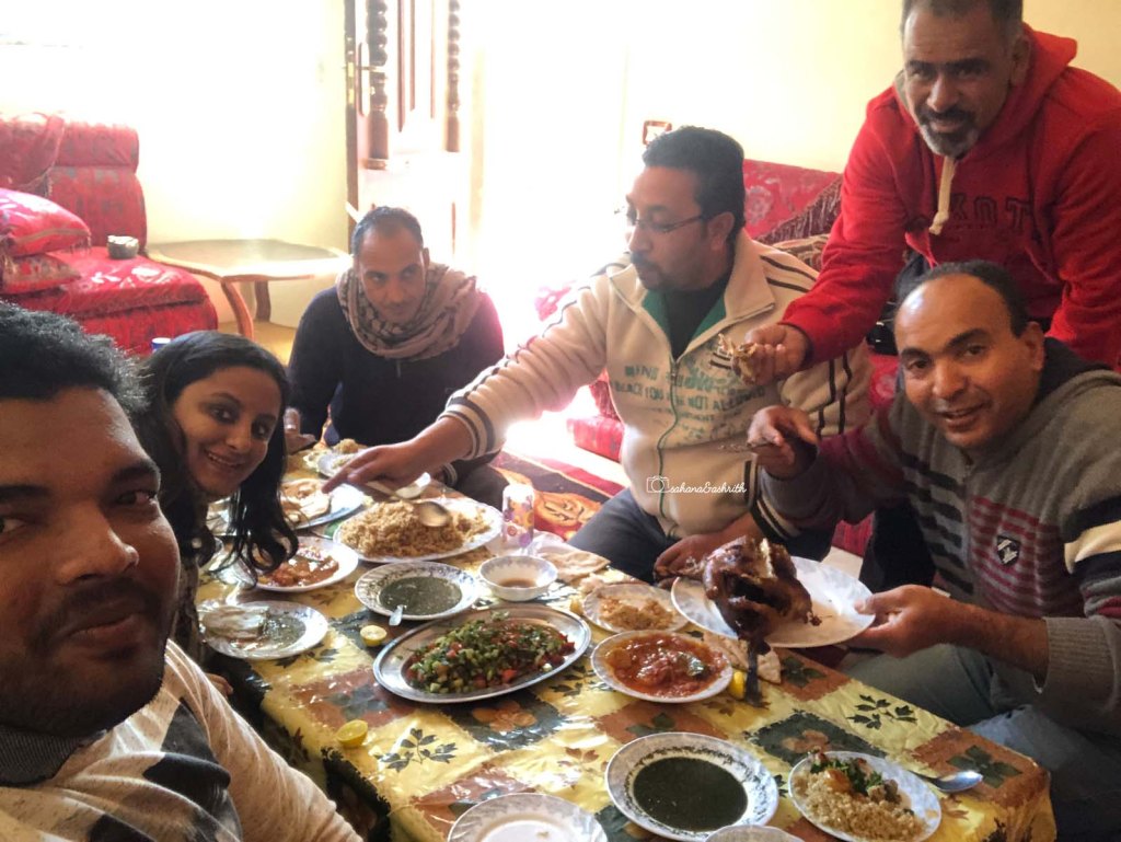 Indian couple travellers having lunch with local Egyptians at a local host house at Bawiti.