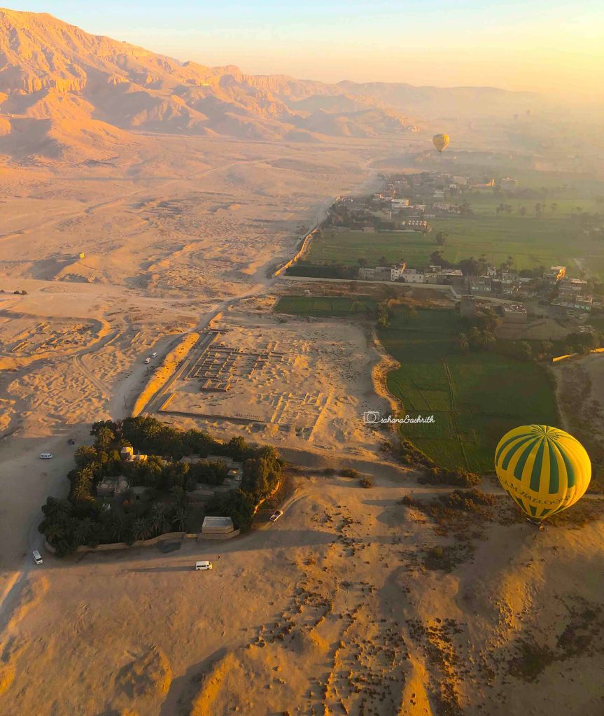 Yellow ballon landing in the desert with fertile land at one corner in Luxor