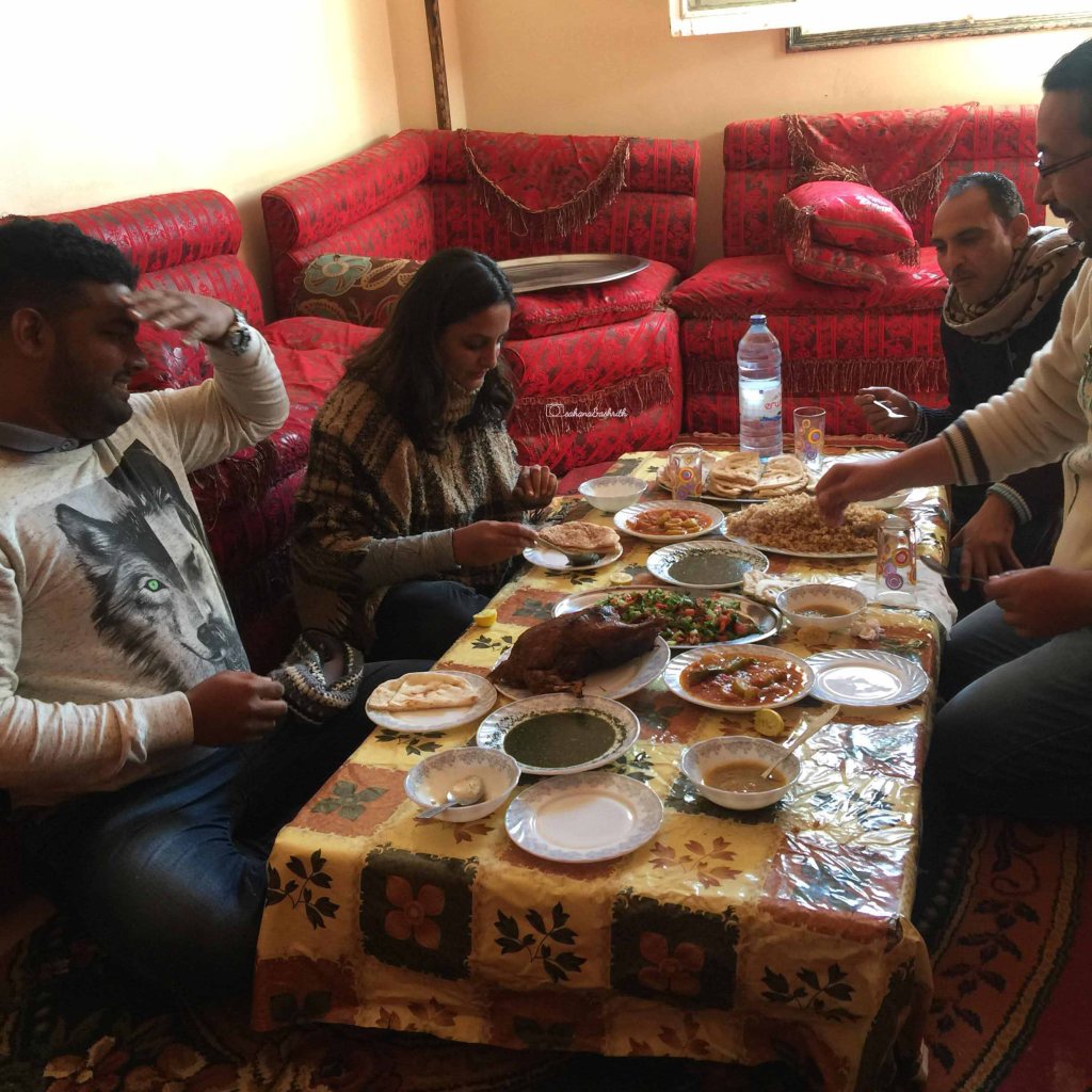 Indian travellers sitting on floor to eat Egypt food with local Egyptians