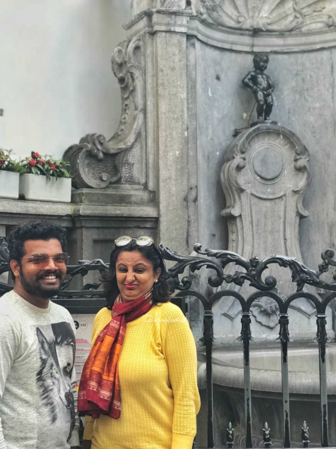Indian couple standing iwith a disgusted face n front of Brussels mannekin pis 