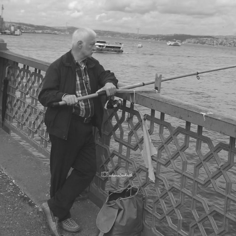 Old Turk catching fish on Galata bridge at Istanbul