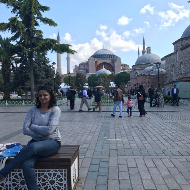 Indian traveller sitting om a bench in front of Hagia Sophia