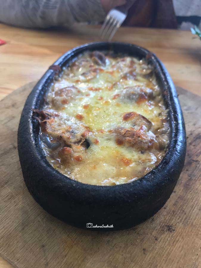 Traditional turkish clay plate containing baked mushroom with kayseri cheese