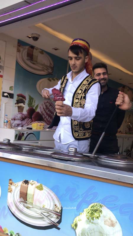 Turkish man in white pant shirt and a embroidered black coat making dondurma