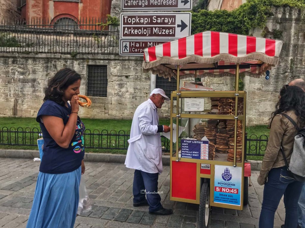 Turks selling simit in front of Blue mosque in Istanbul and Indian traveller eating it