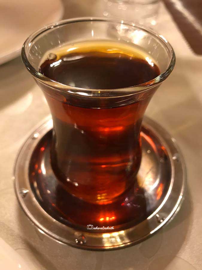 Transparent slim waist traditional Turkish glass containing refreshing brown colour Turkish tea