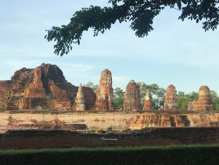 ruins by the road side lined with trees in ayutthaya