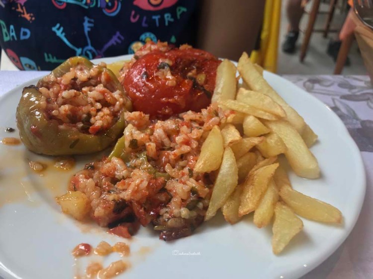Tomatoes filled with flavoured rice and french fries by the side