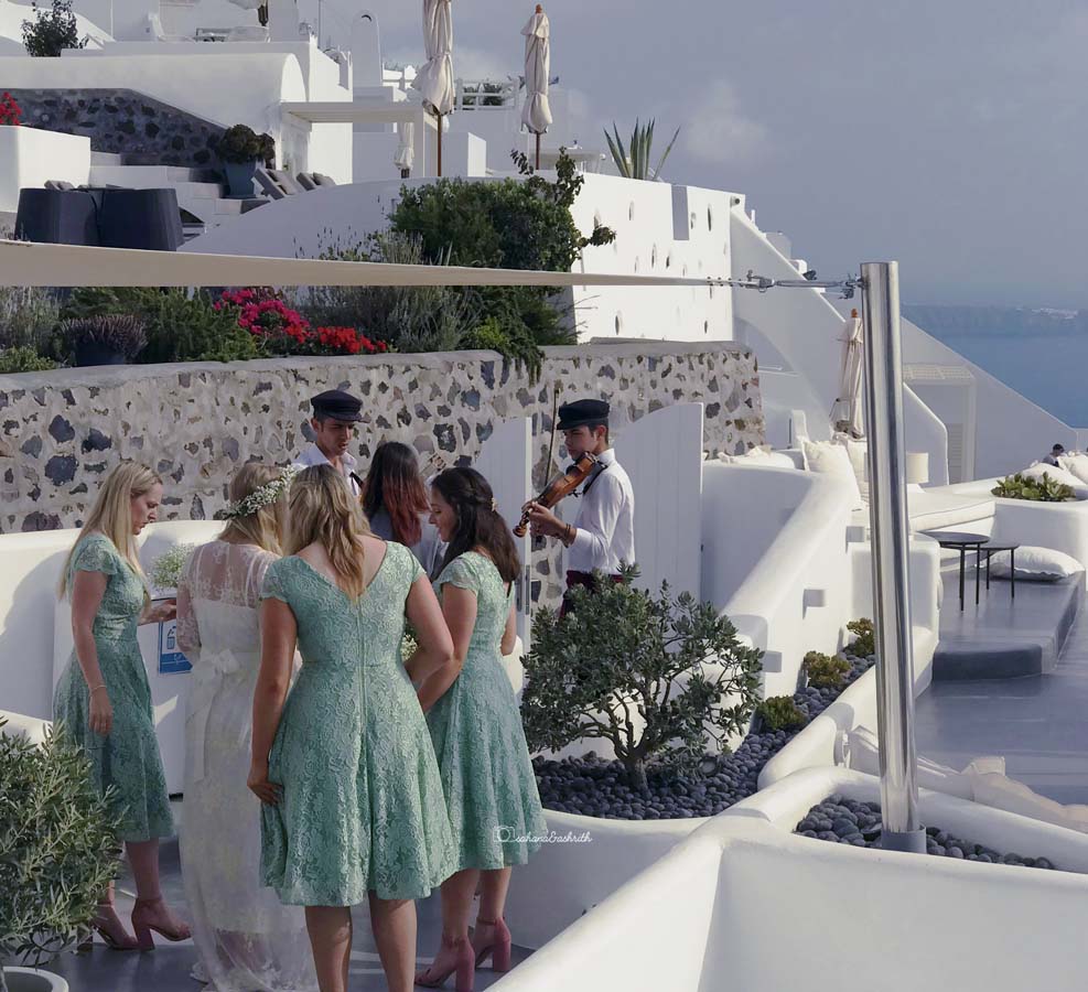 Bridemaids inlight green dress surrounding the bride at Dana Villas Luxury resort in Santorini