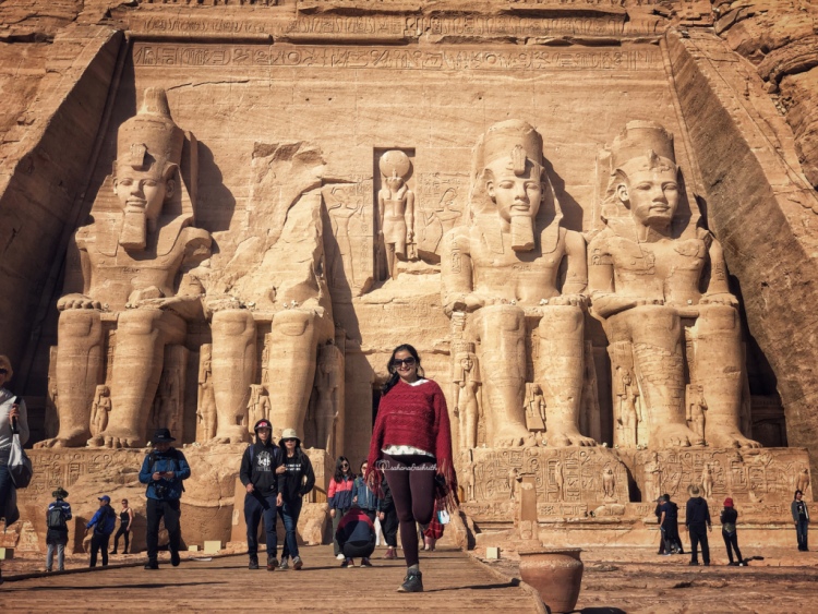 vacaywork author sahana standing infront colossal statues of ramesses at Absu simbel temple entrance.