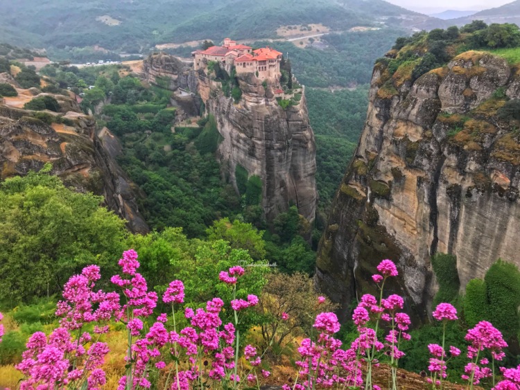Most beautiful view of Meteora monastery on hilltop from the opposite hilltop with flowers