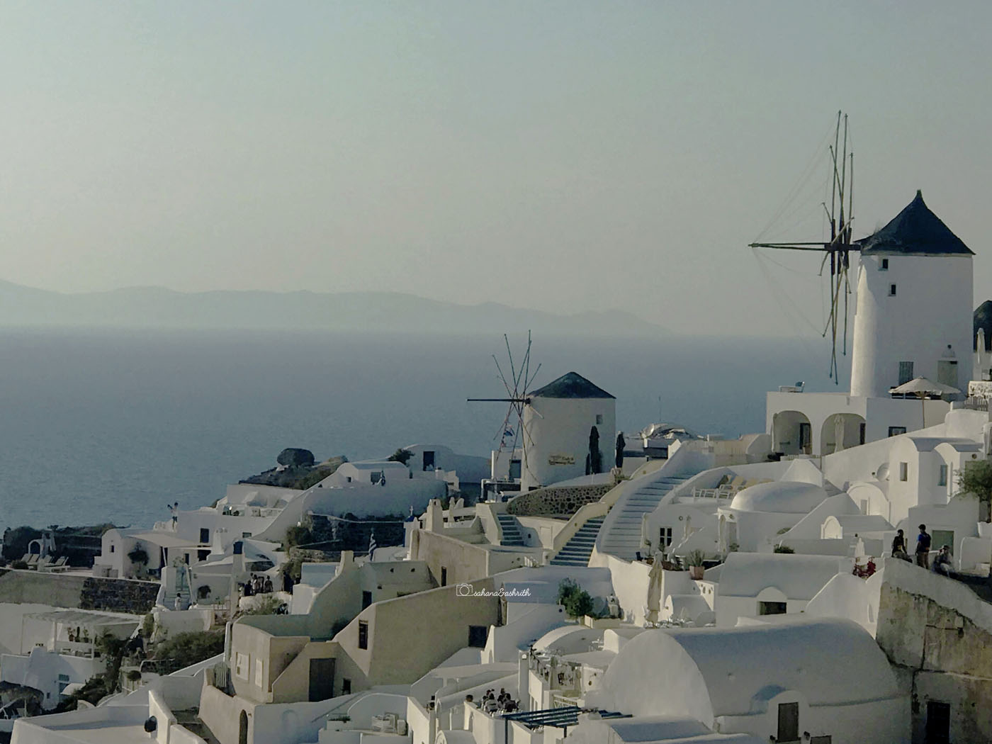 Windmills and cube houses with domes on the terraces at Oia