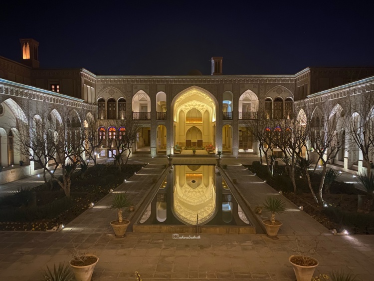 Beautiful reflection of arched entrance way of a luxury mansion in the pond during night at Kashan