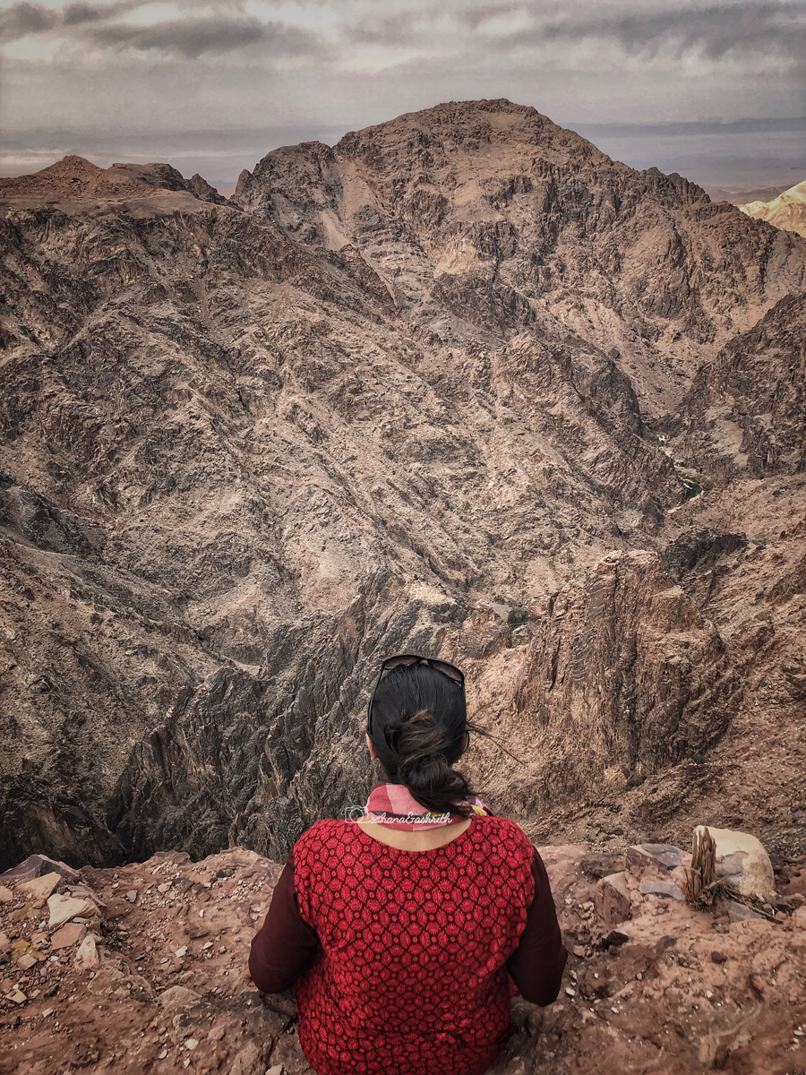 Girl sitting on the edge of cliff at the Petra valley in Jordan