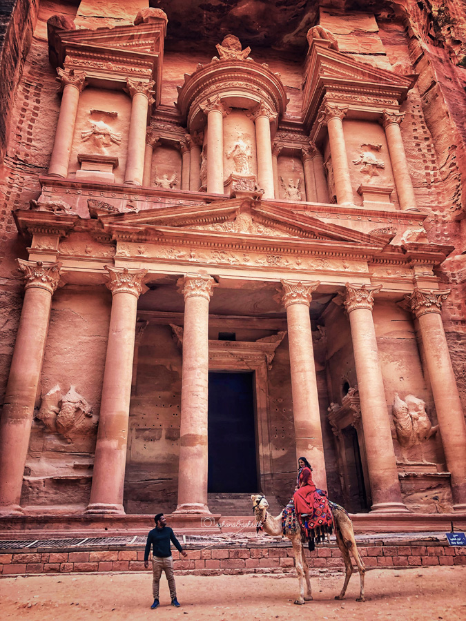 Most beautiful photo of a gril on camel and guy walking along in front of the treasury at Petra