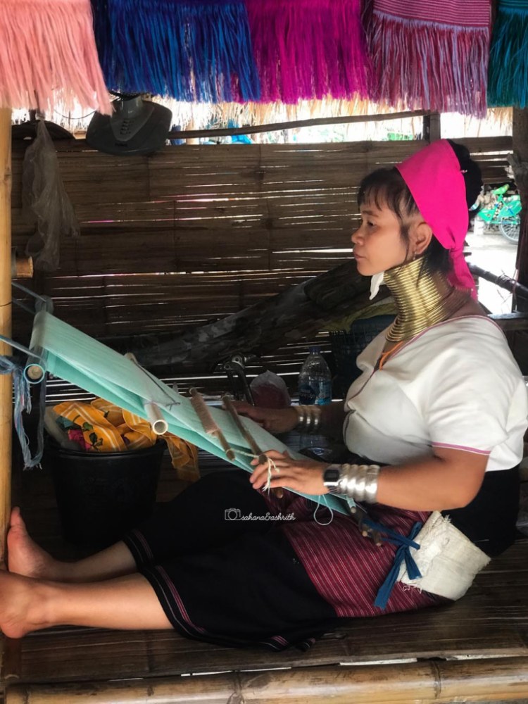 Karen women in Thailand wearing brass rings weaving a scarf