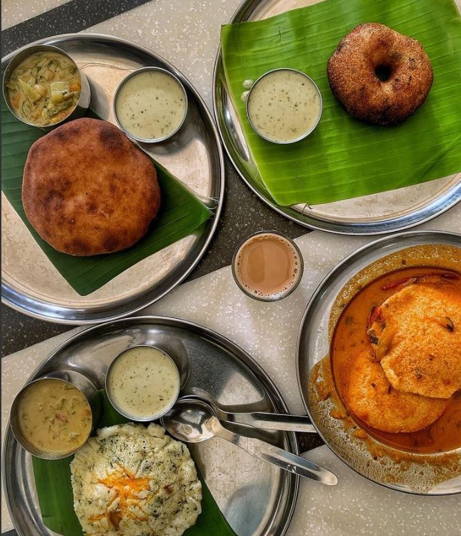 Typical South Indian breakfast on a table - Plate of Banana buns, vada, Idly dipped in sambar and rava idli