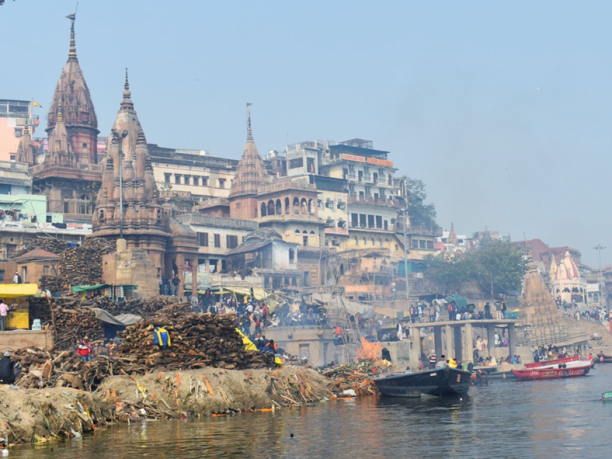 Pile of woods stocked in one corner and the rest burning dead bodies by Ganga in front of a temple in Varanasi