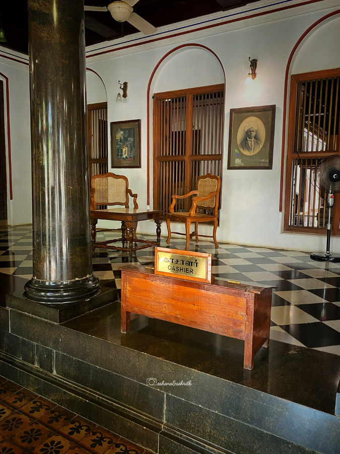 wooden low height cashier desk in an old house with old photos on the wall at a chettinad house