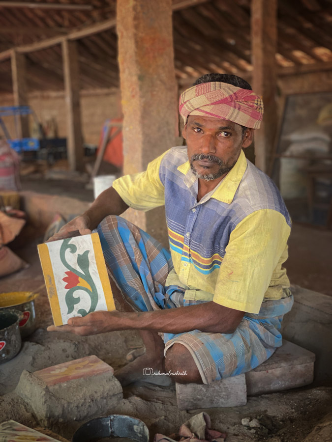 Indian man holding floral patterned rectangular tile made completely by hand